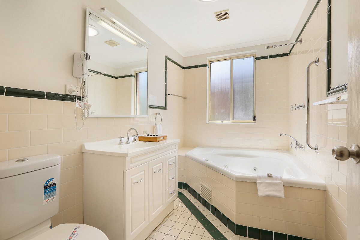 Good size bathroom in our poolside apartment featuring spa bath