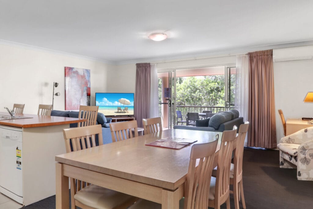 Dining space for six, set beside large windows and sliding door to balcony
